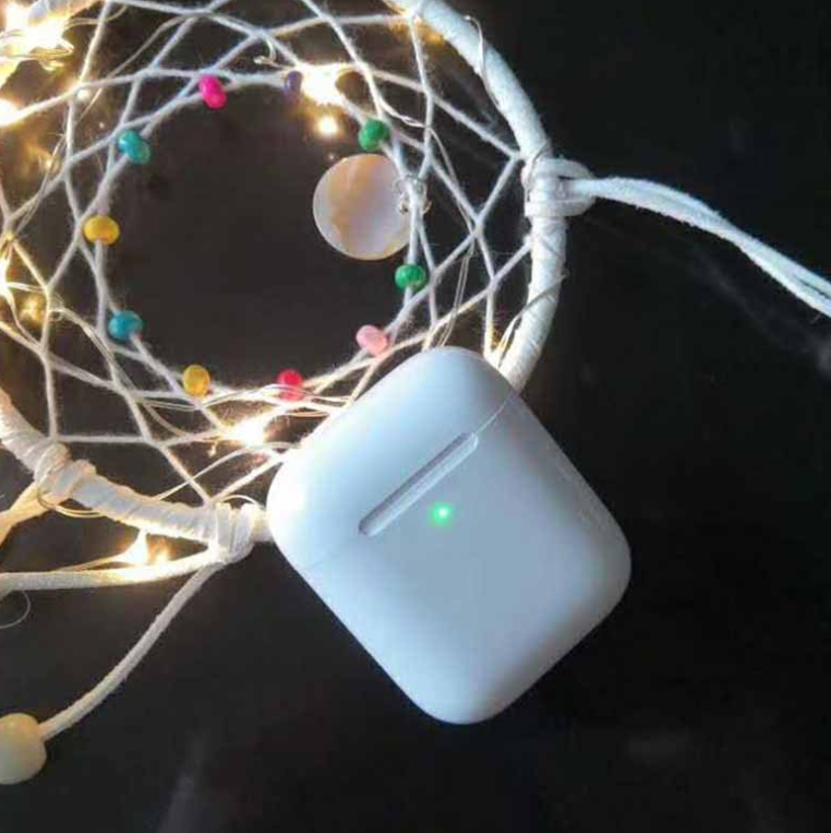 i80 TWS Bluetooth Earbuds with Wireless Charging in a stylish setting with decorative lights.
